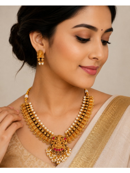 Antique gold temple necklace with Lakshmi pendant, pearl detailing, and matching earrings