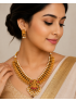 Antique gold temple necklace with Lakshmi pendant, pearl detailing, and matching earrings