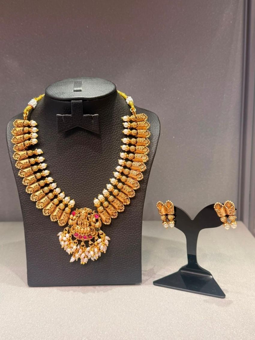 Antique gold temple necklace with Lakshmi pendant, pearl detailing, and matching earrings
