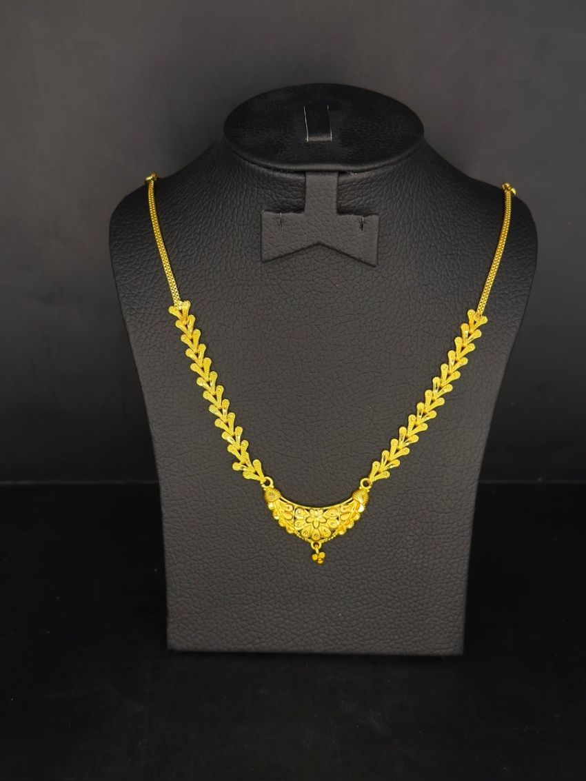 Delicate gold-tone necklace featuring a graceful leaf-pattern chain with an intricately crafted floral pendant.